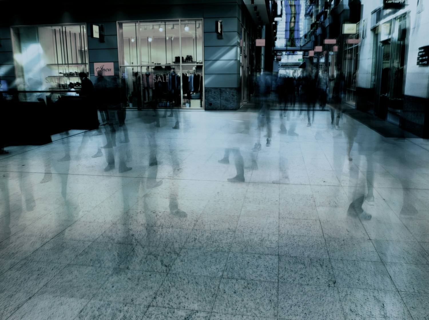 Figures moving through an open concourse, some passing between others